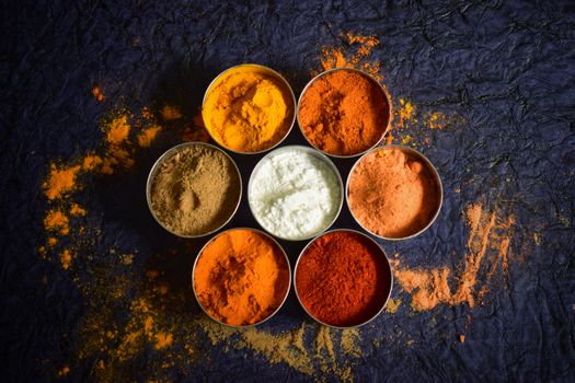 Home Colorful Indian spices in bowls on a textured dark background for culinary concepts.